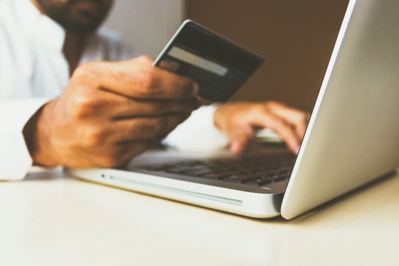 Person holding a card while paying online on a laptop