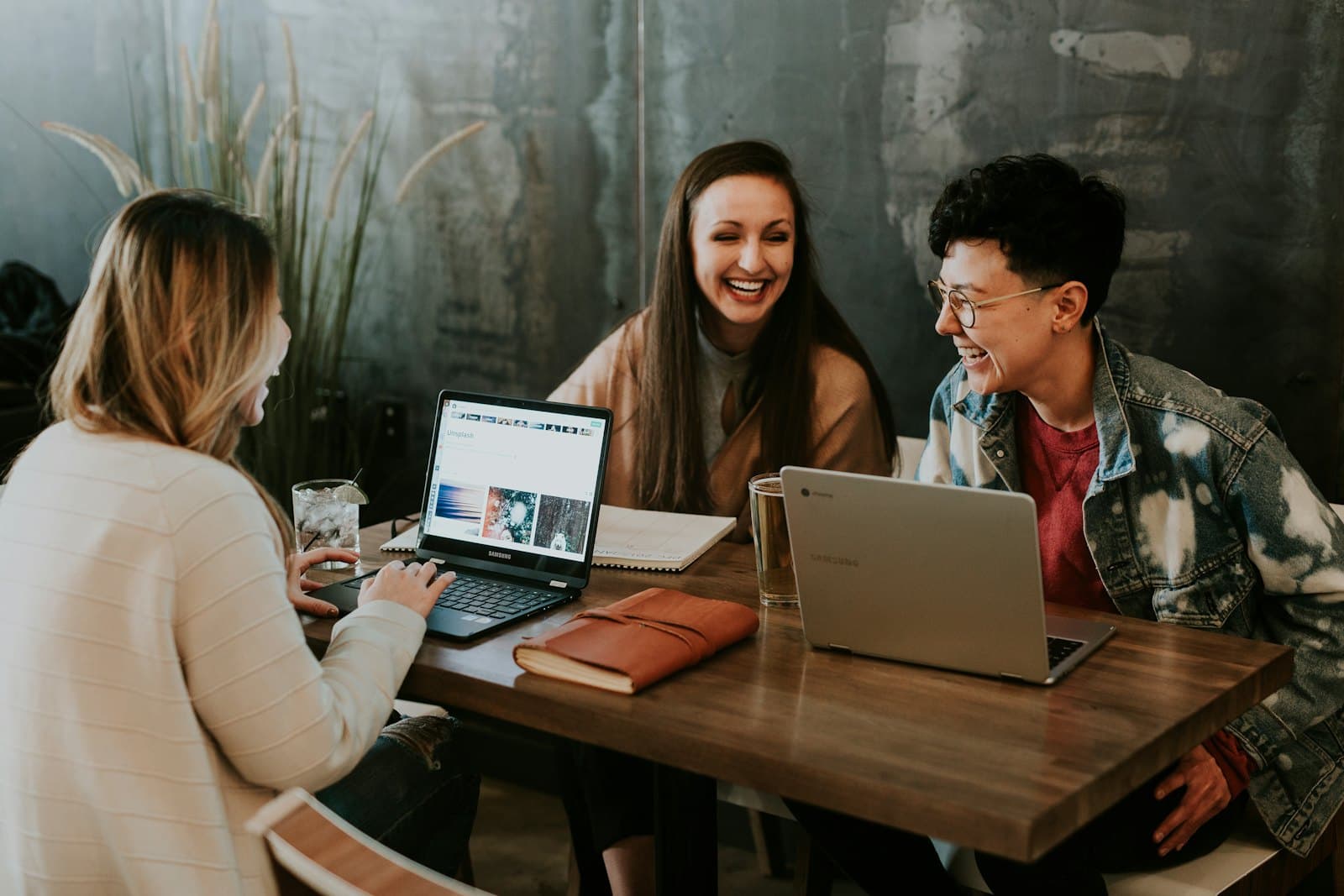 Three colleagues collaborating at a table with laptops